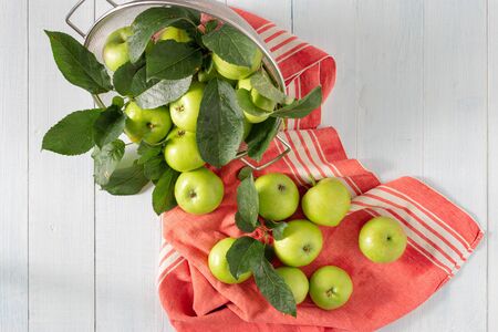 Fresh green apple in colander on a wooden table top viewの写真素材