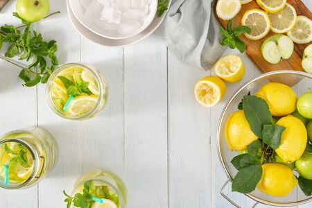 Summer drink concept. Frame from fresh lemonade with apples and lemon on a wooden table top viewの写真素材