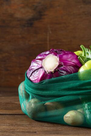 No plastic bag concept. Mesh grocery bag of assorted vegetables on wooden tableの写真素材