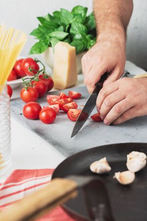 Chef cooking pasta with tomatoes in the home kitchenの写真素材