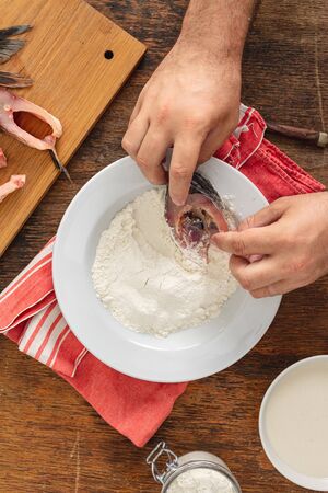 The cook prepares fresh fish on a wooden table in the home kitchenの写真素材