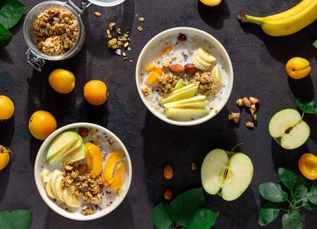 Granola breakfast with fruits, nuts, milk and peanut butter in bowl on a white background. Healthy breakfast cereal top viewの写真素材