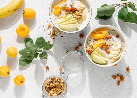 Granola cereal with fruits, nuts, milk and peanut butter in bowl on a white background. Healthy breakfast cereal top viewの写真素材