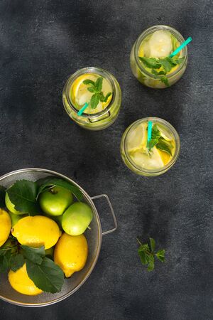 Citrus fruit summer drink concept. Sugar free fresh lemonade with apples and lemon on a dark background top viewの写真素材
