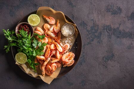 Raw shrimp in a pan with ingredients for cooking on a dark background top viewの写真素材