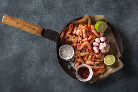 Raw prawns in a cooking pan with ingredients for preparation fried shrimps on a dark background top viewの写真素材