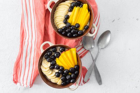 Healthy breakfast table concept. Plate with mango, blueberry, banana on a white background top viewの写真素材