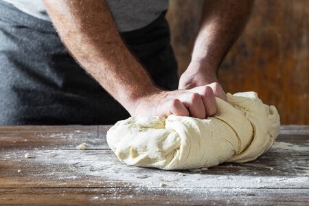 Male hands knead the dough for cooking homemade breadの写真素材