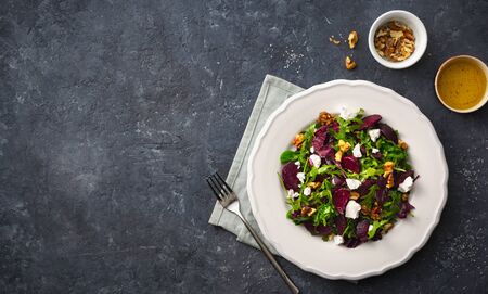 Fresh summer salad with grilled beets, feta cheese and nuts on a dark background top viewの写真素材