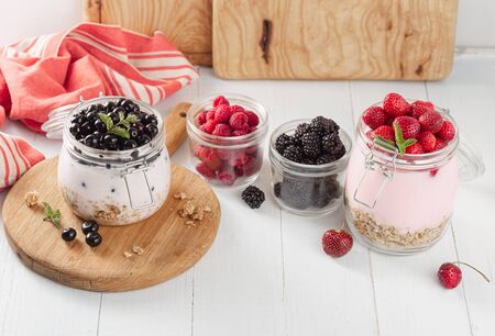 Healthy food breakfast. Granola yogurt with homemade strawberry, blueberry, blackberry and raspberry in glass jar in home kitchenの写真素材