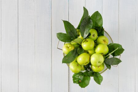 Fresh green apple in colander on a wooden table with copy space top viewの写真素材