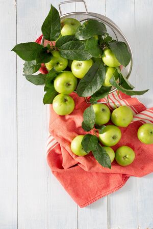 Fresh green apple in colander on a wooden table top viewの写真素材