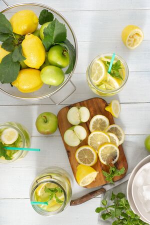 Summer drink concept. Fresh lemonade with apples and lemon on a wooden table top viewの写真素材