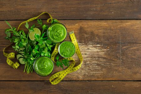 Overhead view green detox smoothie with measuring tape on wooden  food detox conceptの写真素材