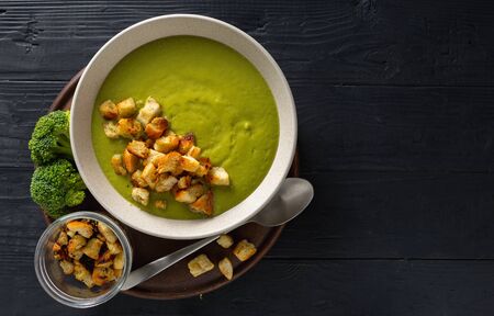 Bowl of cream broccoli soup with bread croutons on a woodenの写真素材