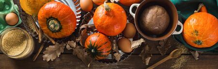 Raw ingredients for cooking pumpkin pie with dry autumn leaves on wooden table close upの写真素材
