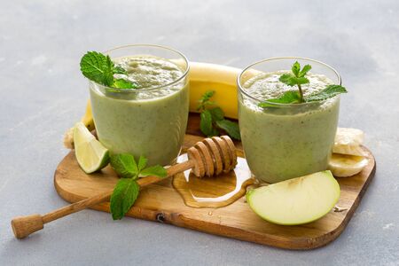 Healthy clean eating concept, Glass mug with green health smoothie of apple spinach lime and honey on a tableの写真素材