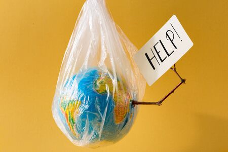 Save our planet concept Earth in a plastic bag  holds card with the inscription helpの写真素材