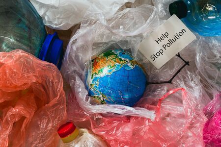 Save our planet or World Environment Day concept Earth in plastic bags holds card with the inscription helpの写真素材