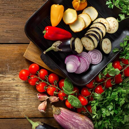 Raw vegetables for cooking on a grill pan on a wooden background top viewの写真素材