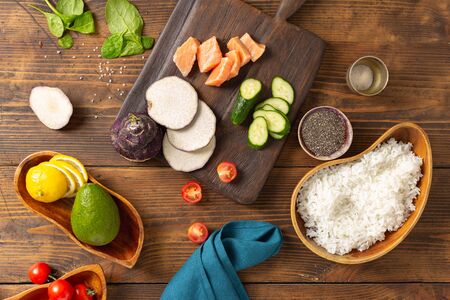Ingredients for preparation poke bowl with salmon, avocado, vegetables and chia seeds on wooden background top viewの写真素材