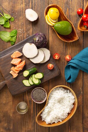 Ingredients for preparation poke bowl with salmon, avocado, vegetables and chia seeds on wooden background top viewの写真素材