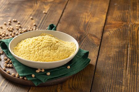 Chickpea flour in white ceramic bowl on wooden table with copy spaceの写真素材