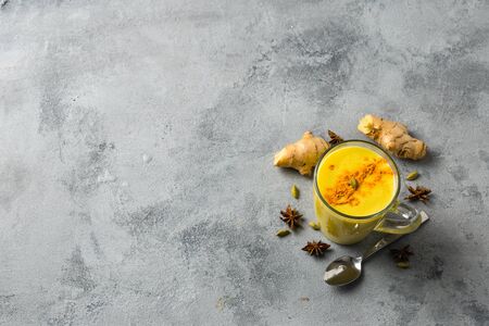 Indian drink turmeric golden milk in glass. Golden latte on light background with ingredients for cooking. Ð¡opy space top viewの写真素材