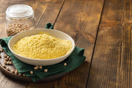 Chickpea flour in white ceramic bowl on wooden table with copy spaceの写真素材