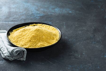 Yellow pea flour in black ceramic bowl on dark background with copy spaceの写真素材