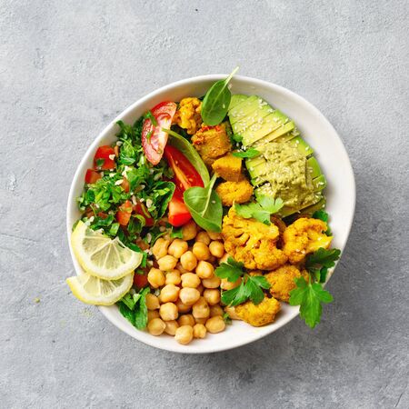 Bowl Buddha. Balanced healthy vegetarian food. Aloo gobi, tabouli salad, chickpeas, avocado, tomato and spinach. Top view. Free space for your textの写真素材