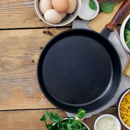 Healthy breakfast table with empty cooking pan and ingredient for cooking on wooden background top view copy space. Broccoli, eggs, spinach and cheese on tableの写真素材
