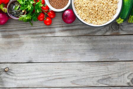 Diet and healthy food concept. Green buckwheat, sunflower and flax seeds, vegetables and greens top view on wooden white background with copy spaceの写真素材
