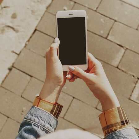 Female hands holding a smartphone with a blank screenの写真素材