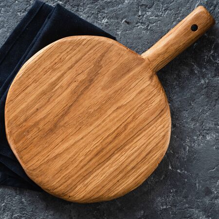 Empty wooden cutting board on dark stone background top viewの写真素材