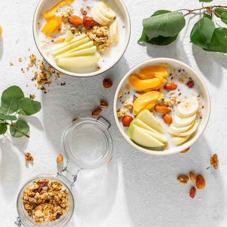 Granola cereal with fruits, nuts, milk and peanut butter in bowl on a white background. Healthy breakfast cereal top view の写真素材