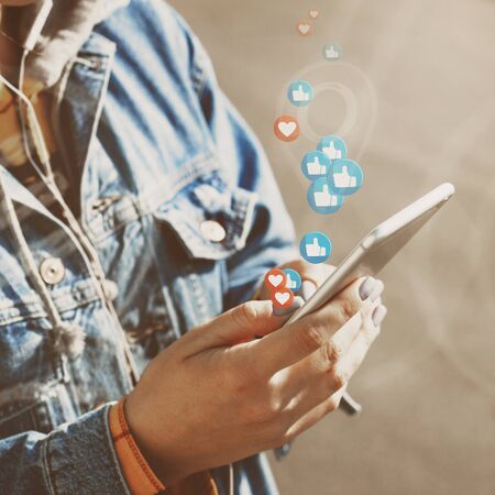 Young woman watches live stream while walking down city streetの写真素材