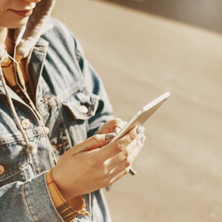 Young woman blogger browsing social networks on the street. Woman texting on her phoneの写真素材