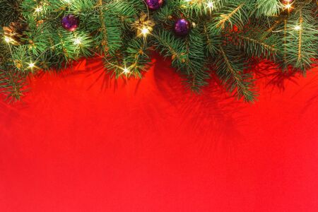 Spruce branches with christmas balls and garland on a red background top viewの写真素材