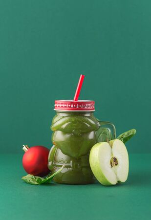 Zero waste concept. Green apple spinach smoothie on green background in glass santa claus jar. Healthy and diet food conceptの写真素材