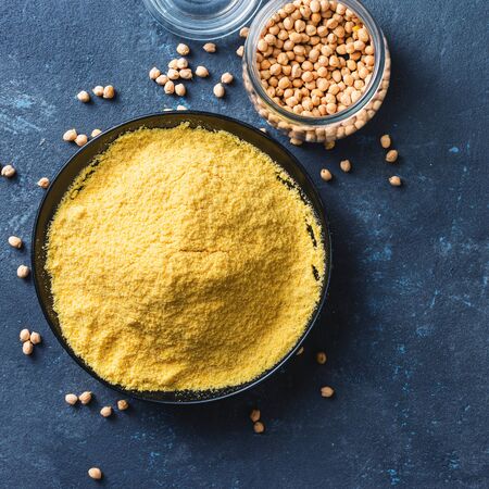 Yellow pea flour in black ceramic bowl on dark background top view with copy spaceの写真素材