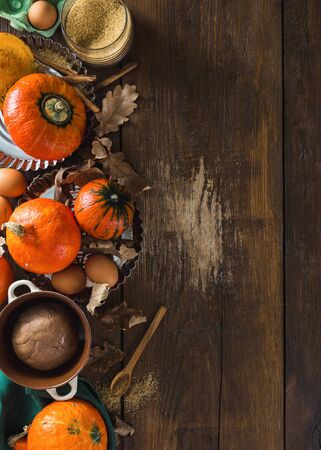 Raw ingredients for cooking pumpkin pie with dry autumn leaves on wooden background with copy spaceの写真素材