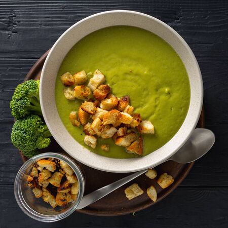 Bowl of cream broccoli soup with bread croutons on a wooden backgroundの写真素材