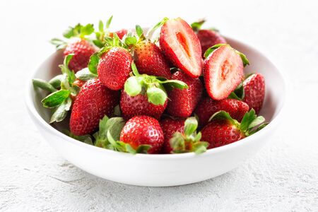 Heap of fresh strawberries in ceramic bowl on white backgroundの写真素材