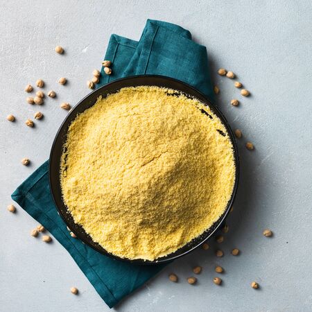 Chickpea flour in black ceramic bowl on light background top view with copy spaceの写真素材