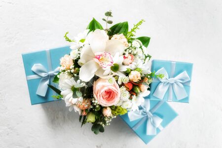 Flower bouquet with blue gift boxes on white background flat lay top viewの写真素材