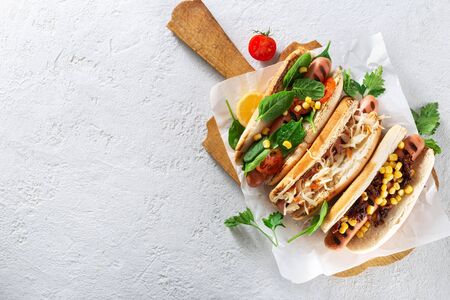 Three different hot dog grills served in pan on a wooden board on light background. Copy space top viewの写真素材