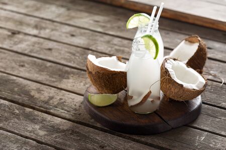 Coconut water in bottles on wooden table. Healthy veggie drinkの写真素材