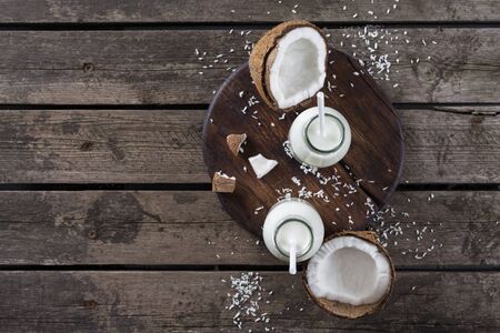 Coconut milk in glass bottle on wooden table. Vegan non dairy healthy drink. Healthy eating conceptの写真素材