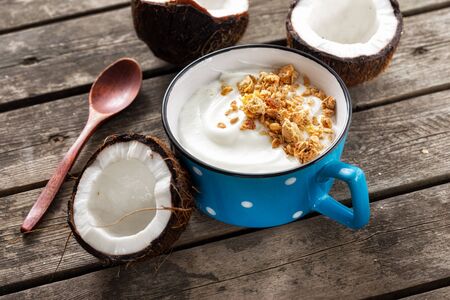 Coconut yogurt with granola in cup on wooden table. Probiotic food concept. Tasty and healthy breakfastの写真素材